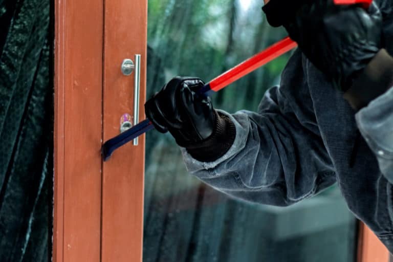 burglar with crowbar trying break door enter house